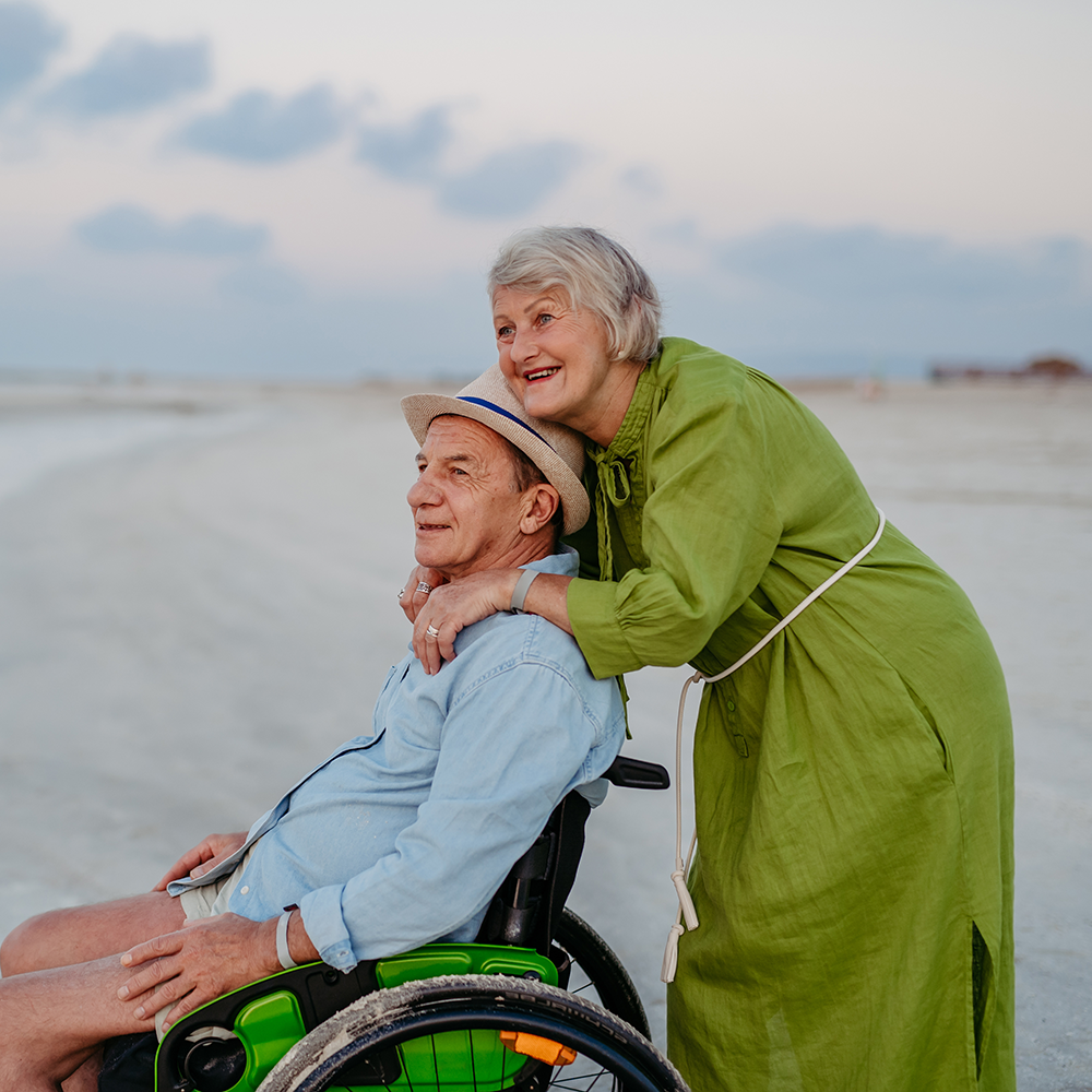 man in wheelchair on beach with wife